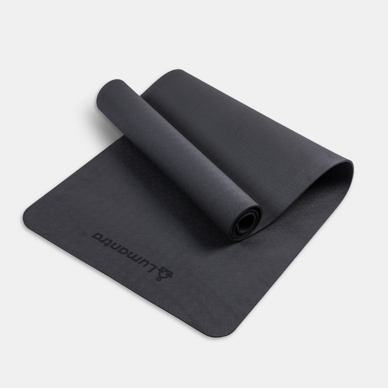 Black Lumantra yoga mat rolled partially open, showcasing its eco-friendly texture and non-slip surface.