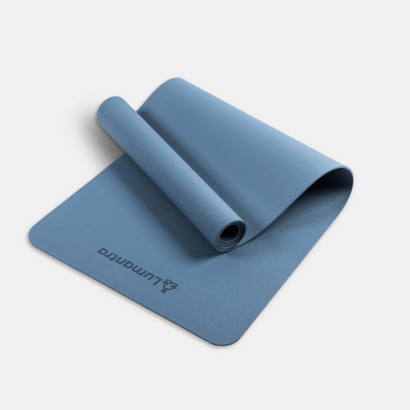 Blue Lumantra yoga mat rolled partially open, showcasing its eco-friendly texture and non-slip surface.